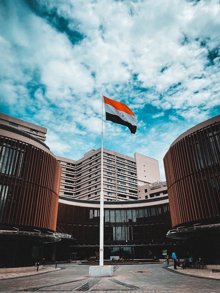 about-02 Indian flag waving against a backdrop of modern architecture in Delhi, India.